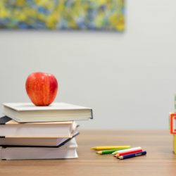 Apple on top of a stack of books on a desk