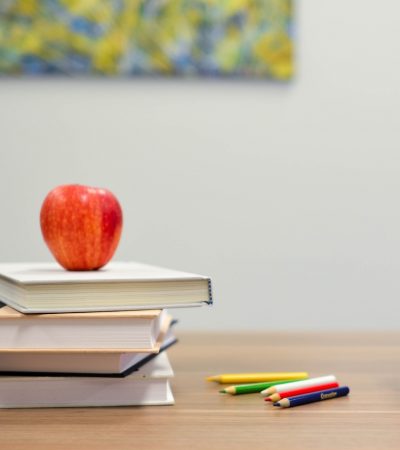 Apple on top of a stack of books on a desk