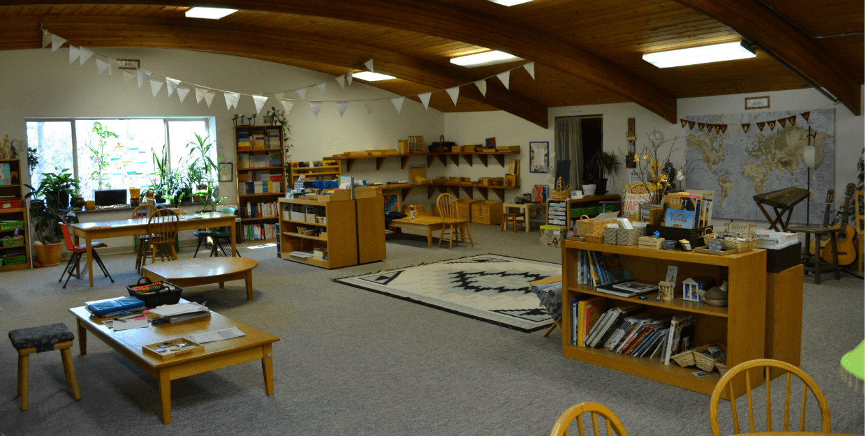 classroom with bookshelves, tables, and materials
