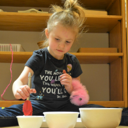 Child scooping materials into three bowls